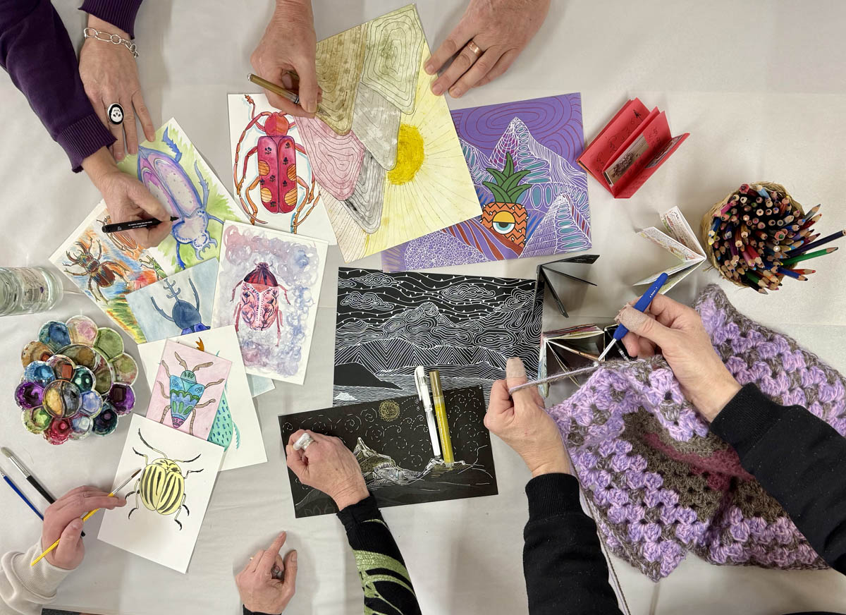 hands reach to sketch, paint and crochet